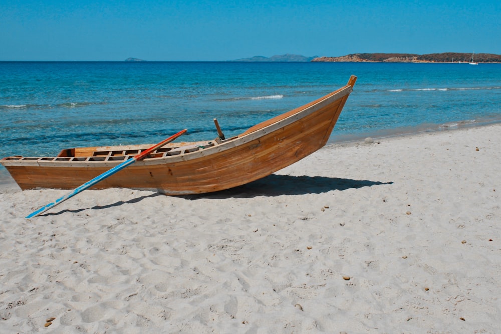brown wooden boat on white sand beach during daytime