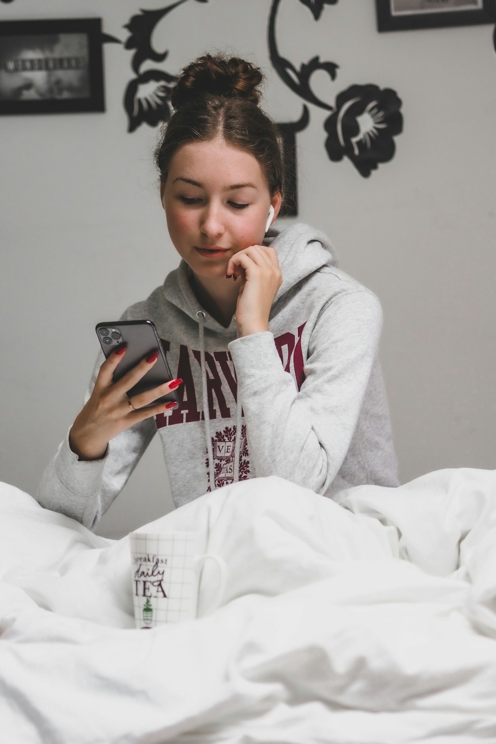 woman in gray hoodie holding black smartphone