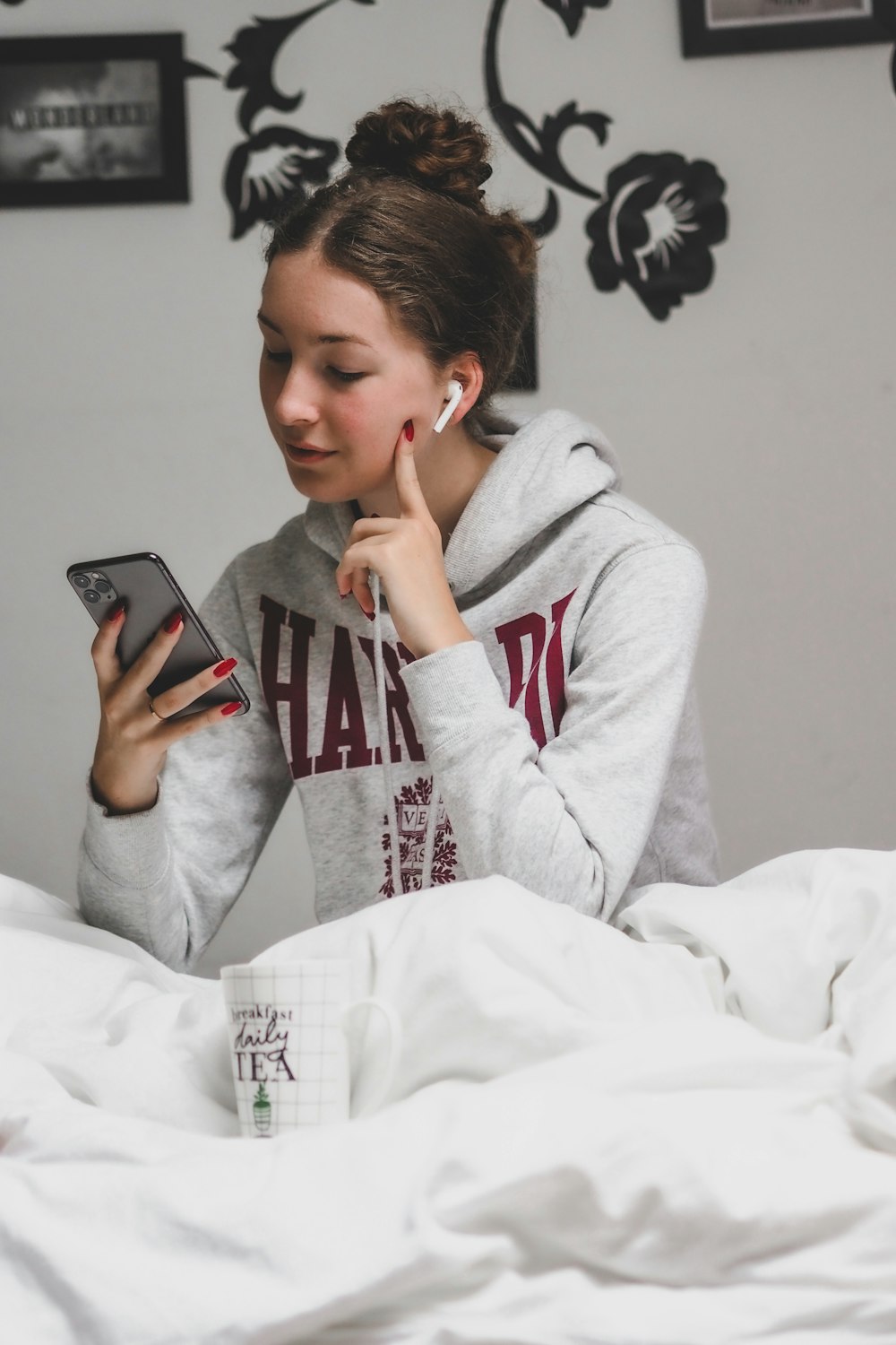 woman in gray hoodie holding black smartphone