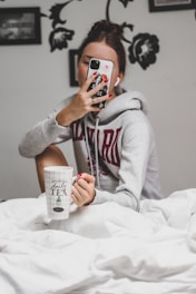 woman in gray hoodie holding white ceramic mug