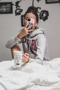 woman in gray hoodie holding white ceramic mug