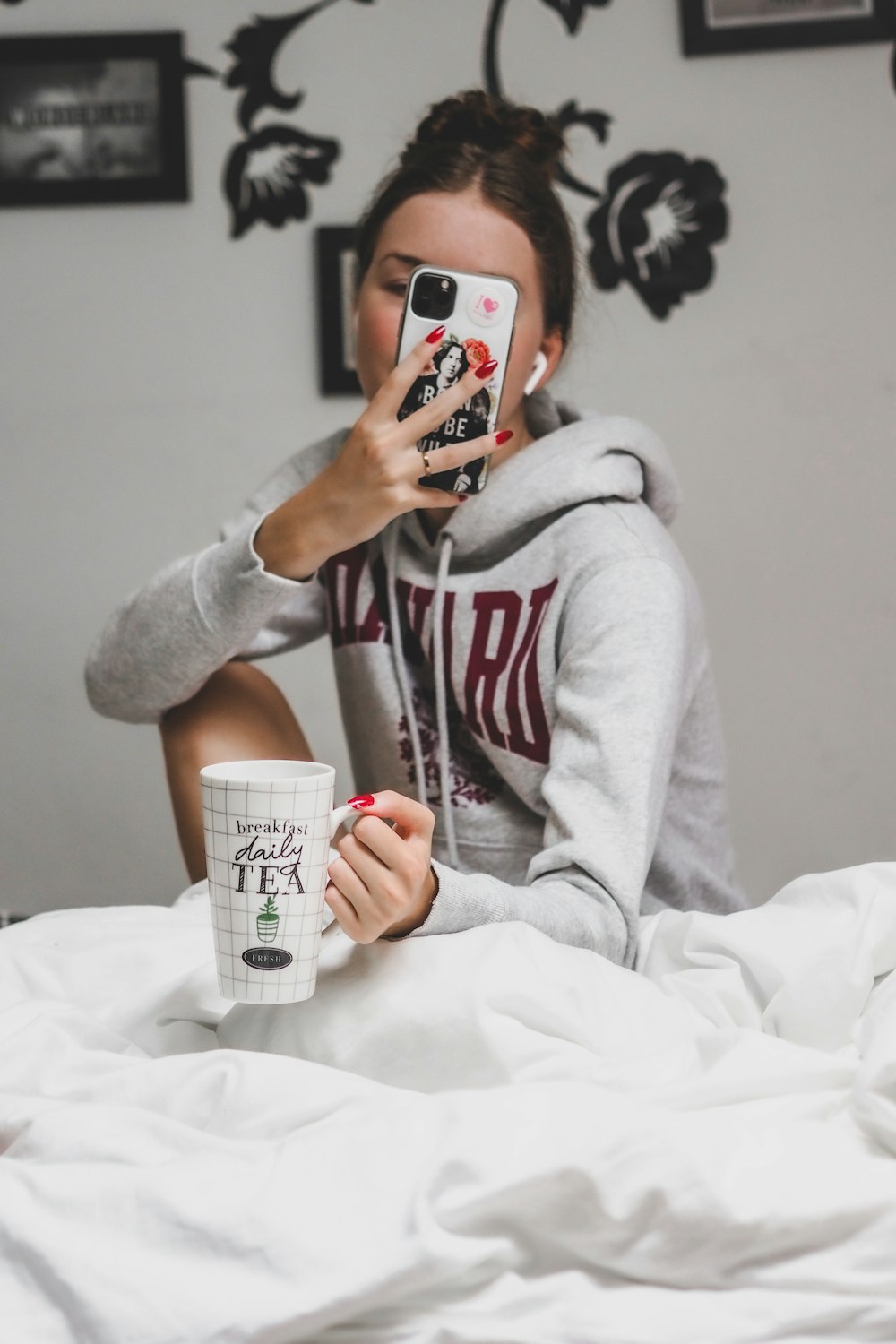 mujer con sudadera con capucha gris sosteniendo una taza de cerámica blanca