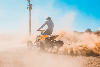 man riding on yellow and black atv