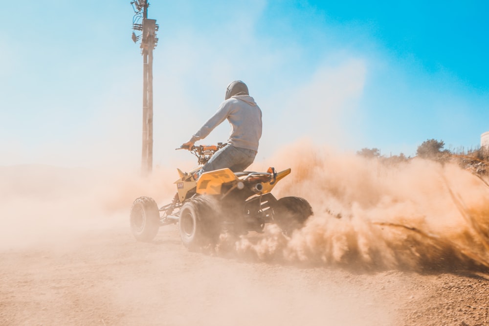 Uomo che cavalca su ATV giallo e nero