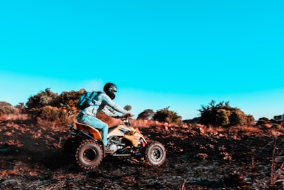 man riding atv on brown field during daytime suzuki teams background