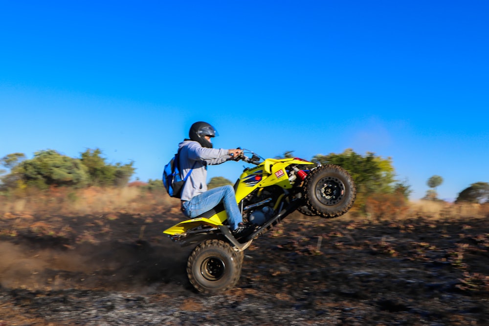 man in blue jacket riding yellow atv