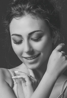 Close-up of a serene woman smiling gently while journaling in a cozy, feminine workspace
