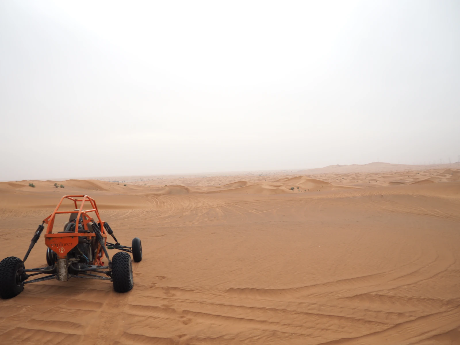 Red and black dune buggy parked on desert sand in daylight