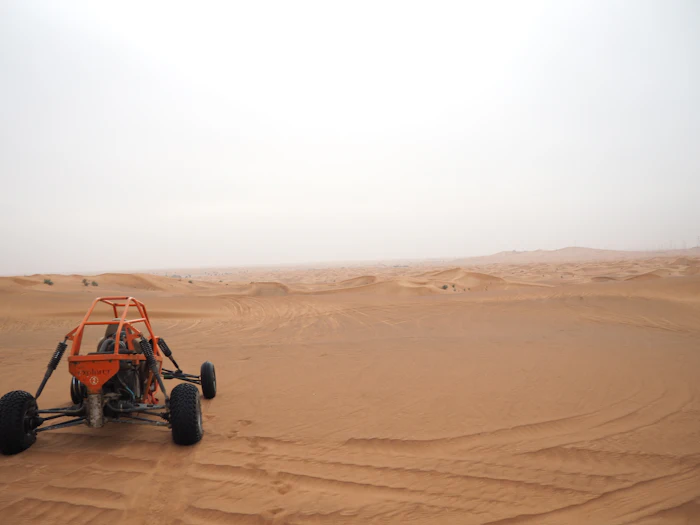 Red and black dune buggy on desert sand