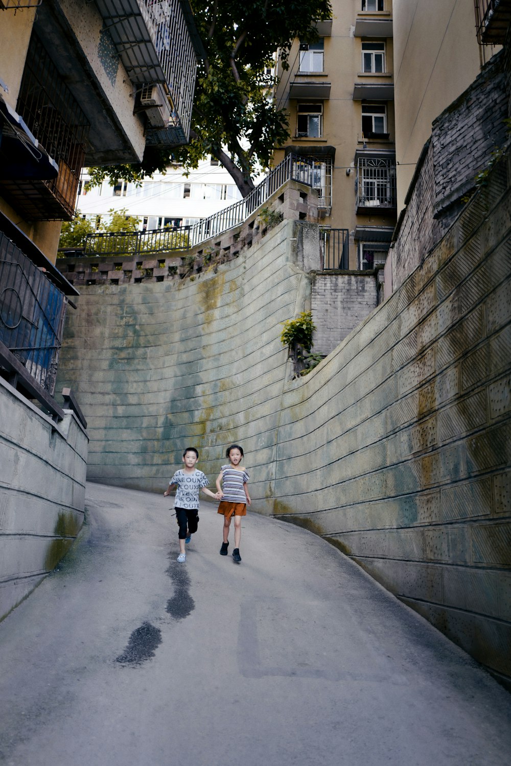 girl in white long sleeve shirt and white pants walking on gray concrete pathway during daytime