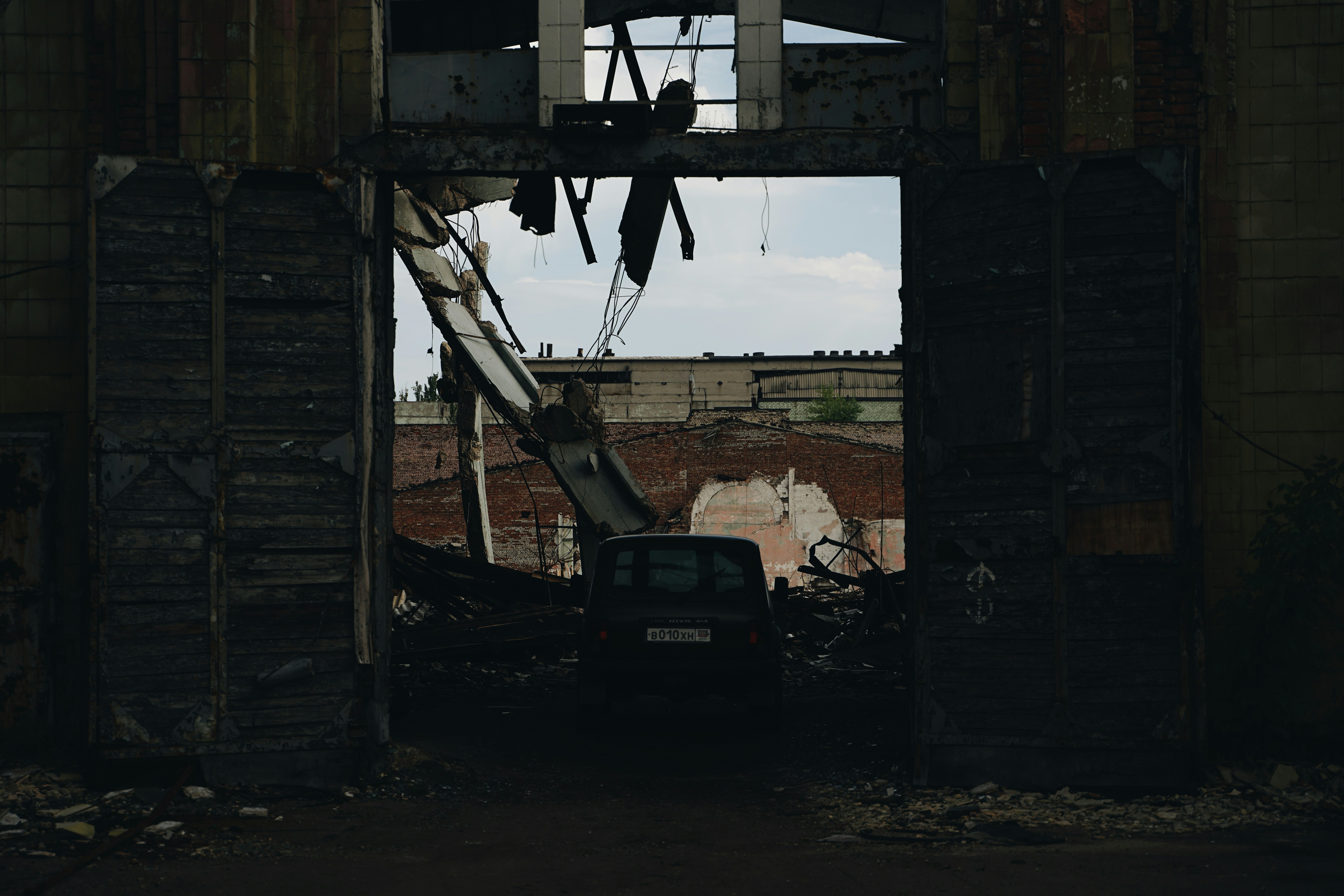 black car parked beside brown wooden house during daytime