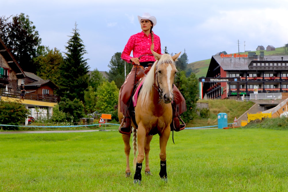 girl in pink long sleeve shirt riding brown horse during daytime
