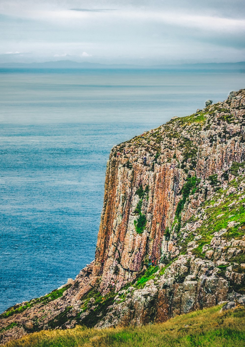 brown and green rock formation beside blue sea during daytime