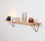 A sleek floating shelf mounted on a white wall holding a mix of books and decorative items.