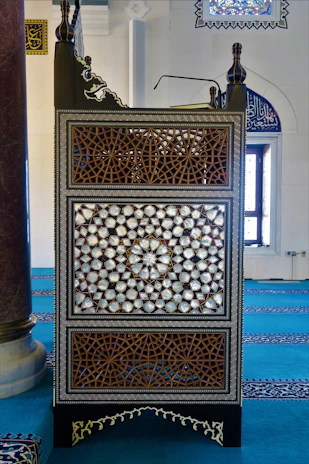 A beautifully crafted wooden mimber with intricate carvings in a mosque setting.