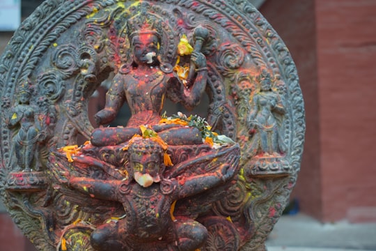 woman in blue dress sitting on rock statue in Patan Nepal