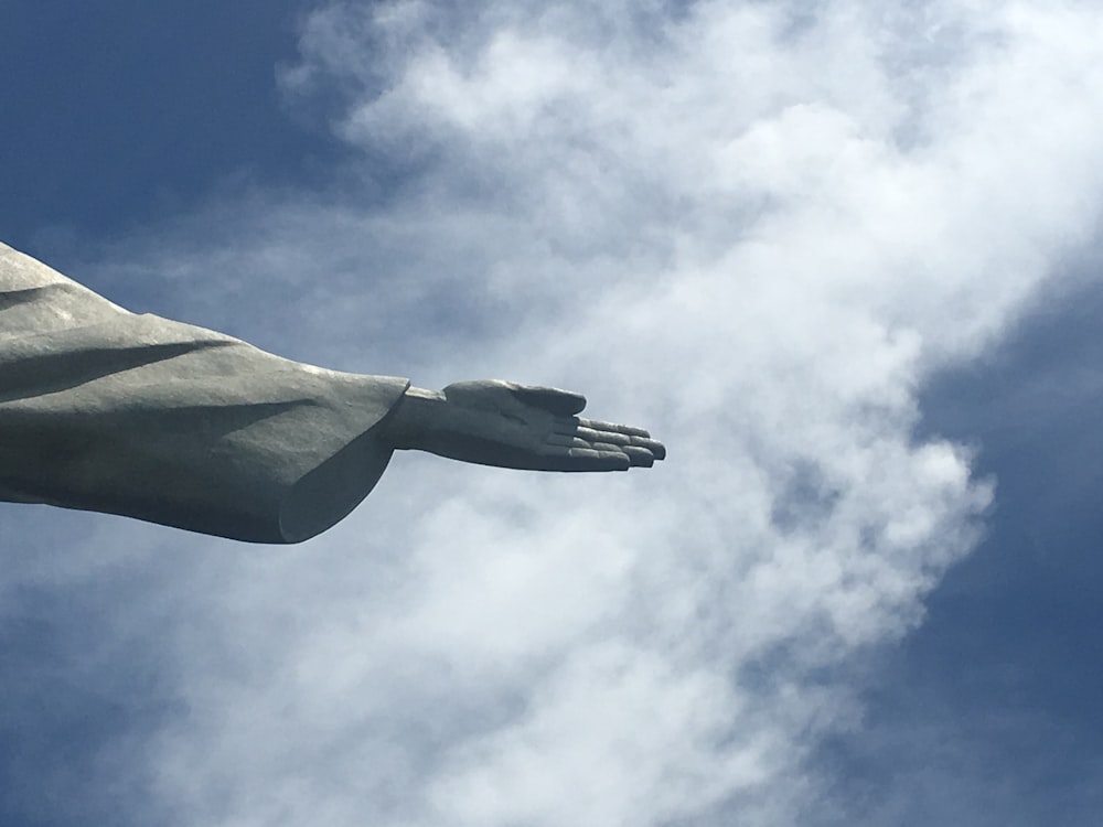 Photographie en contre-plongée d’une statue en béton gris sous un ciel bleu pendant la journée