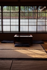 Interior view of a minimalist Japanese room with floor cushions and low table.
