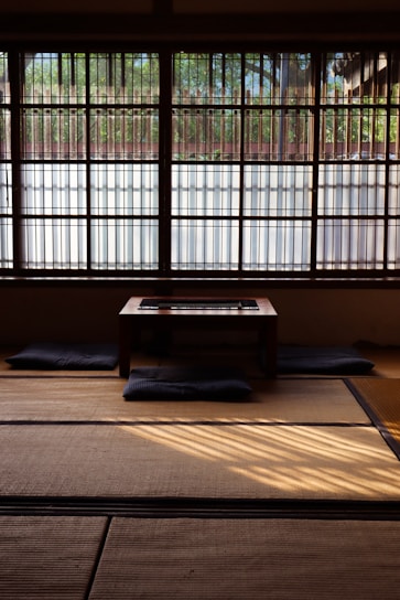 Interior view of a minimalist Japanese room with floor cushions and low table.