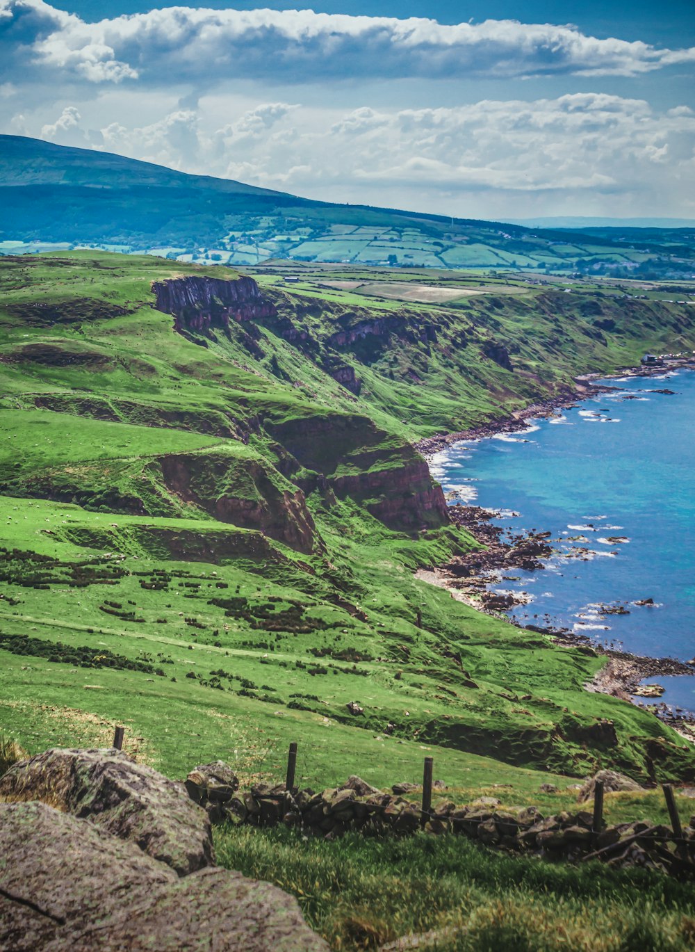 green grass covered mountain near body of water during daytime