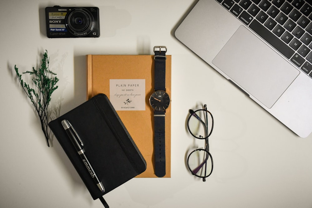 black framed eyeglasses beside black leather case and macbook pro