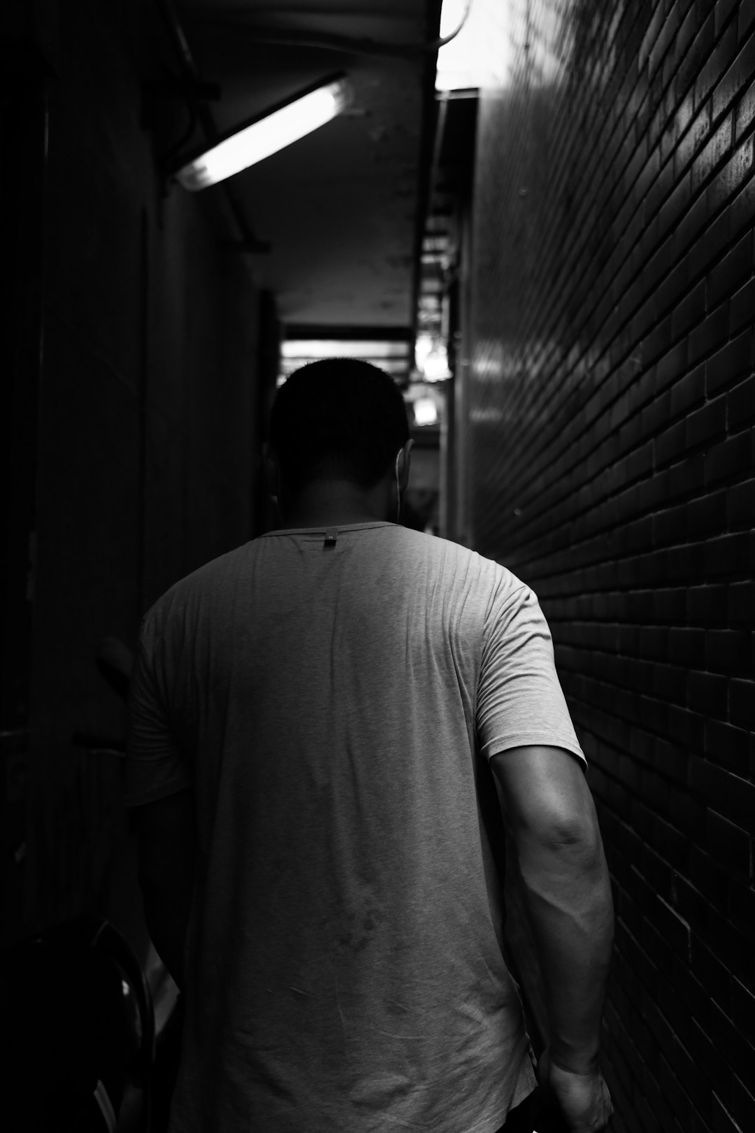 man in white crew neck t-shirt standing in grayscale photography