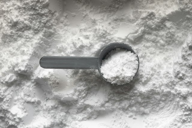 A measuring scoop filled with white creatine powder