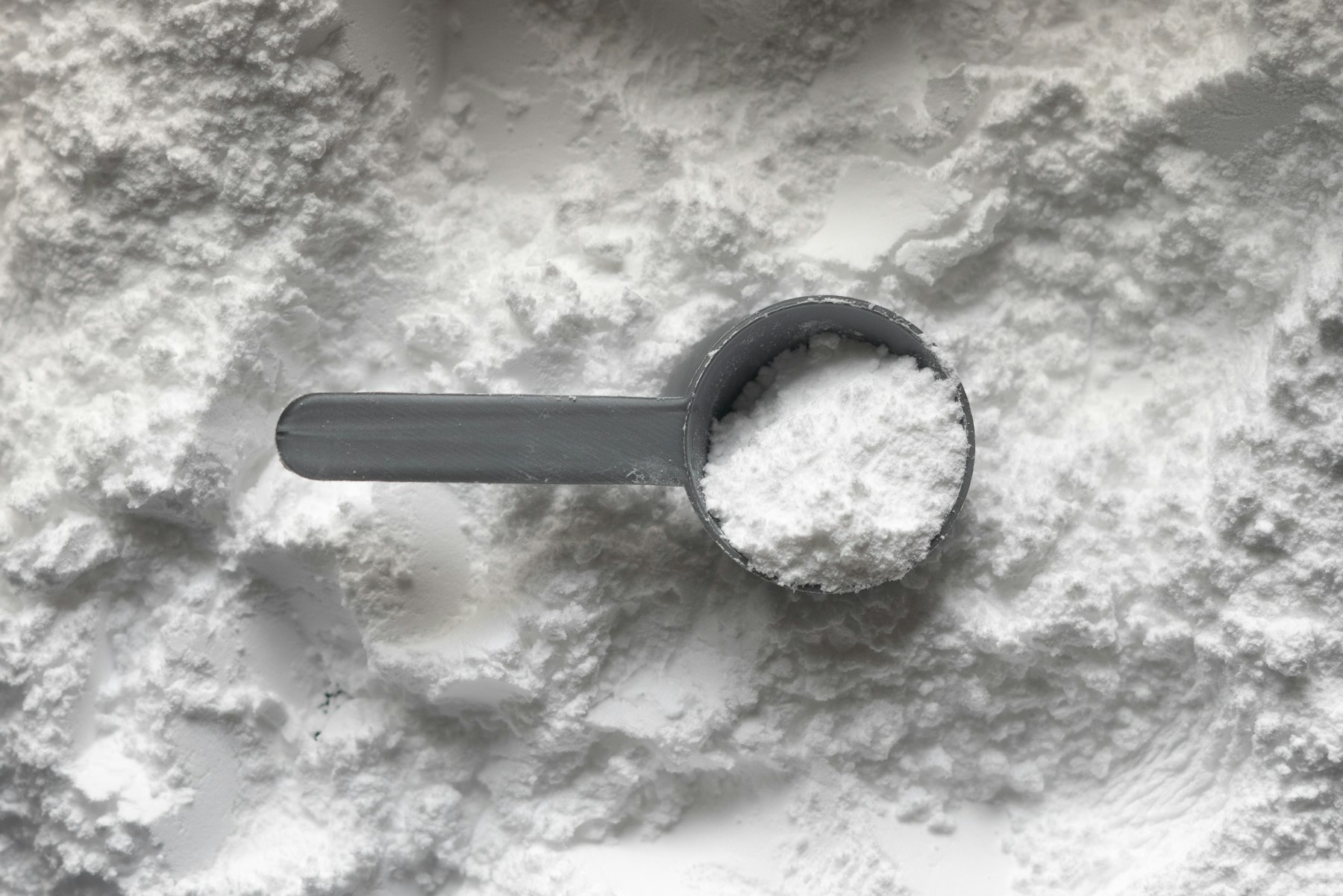 A scoop of white powder resting on a pile of powder