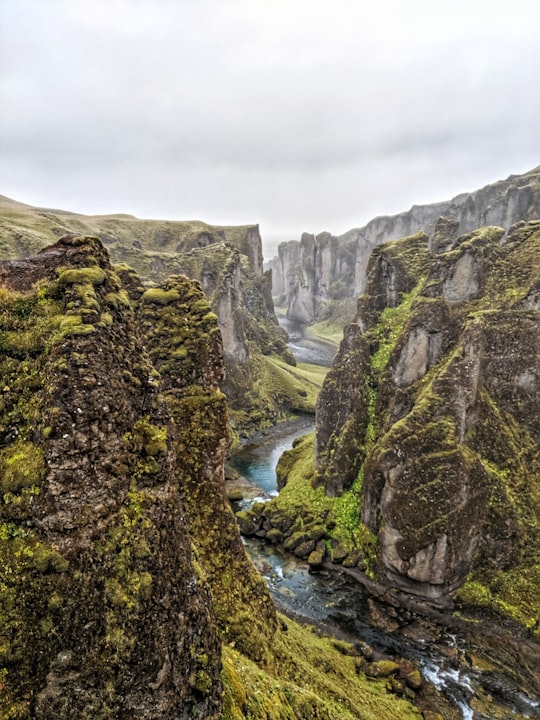 grayscale photo of river between rocky mountains in Fjaðrárgljúfur Iceland