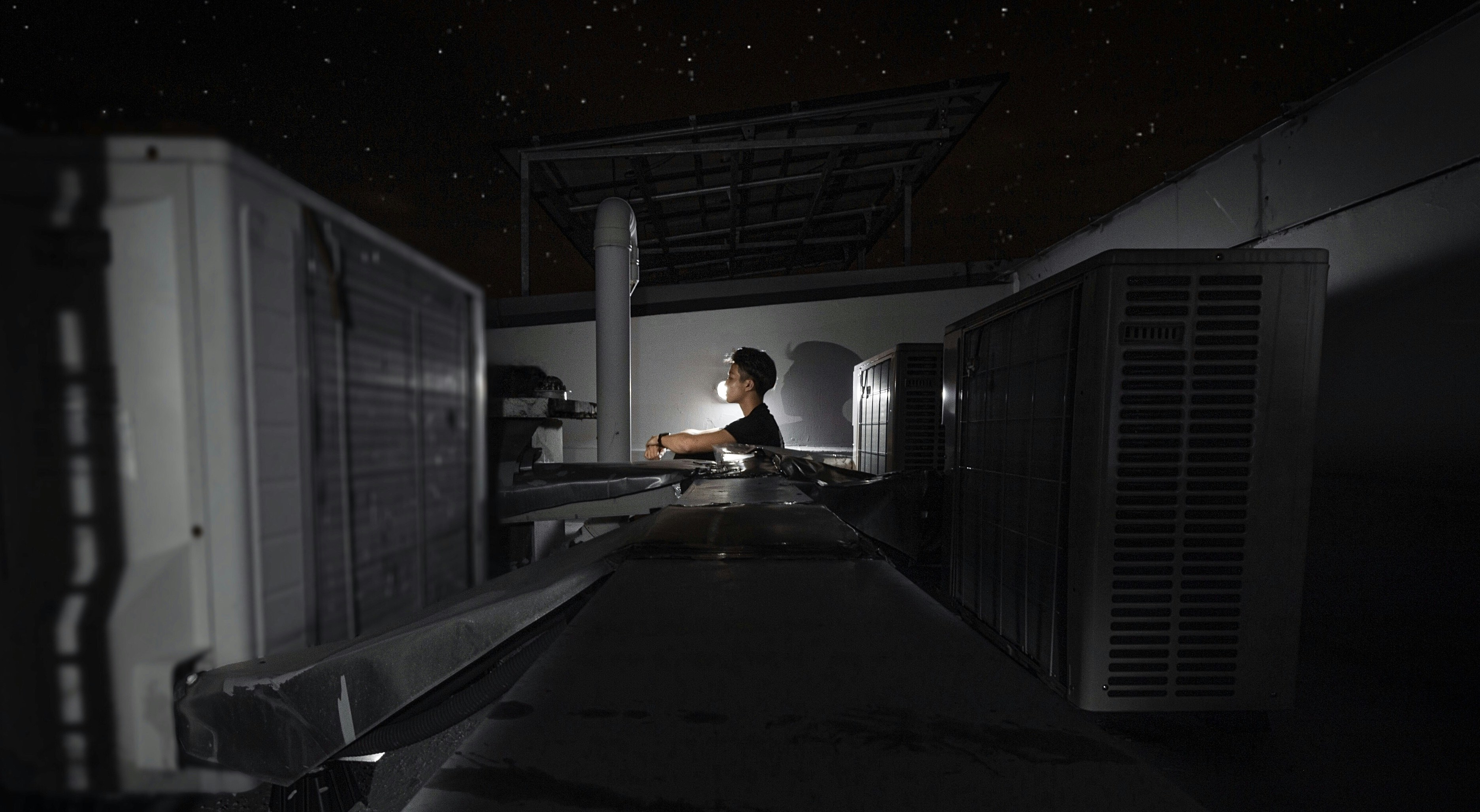 man in white t-shirt and black pants sitting on black wooden table
