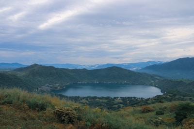 Bright Star Safari Lodge guests enjoying a picnic by a sparkling crater lake, surrounded by lush greenery and distant hills.