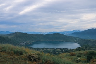 Bright Star Safari Lodge guests enjoying a picnic by a sparkling crater lake, surrounded by lush greenery and distant hills.