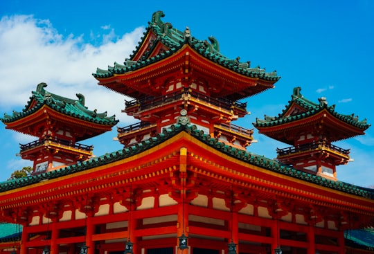 red and black pagoda temple under blue sky during daytime in Heian Shrine Japan