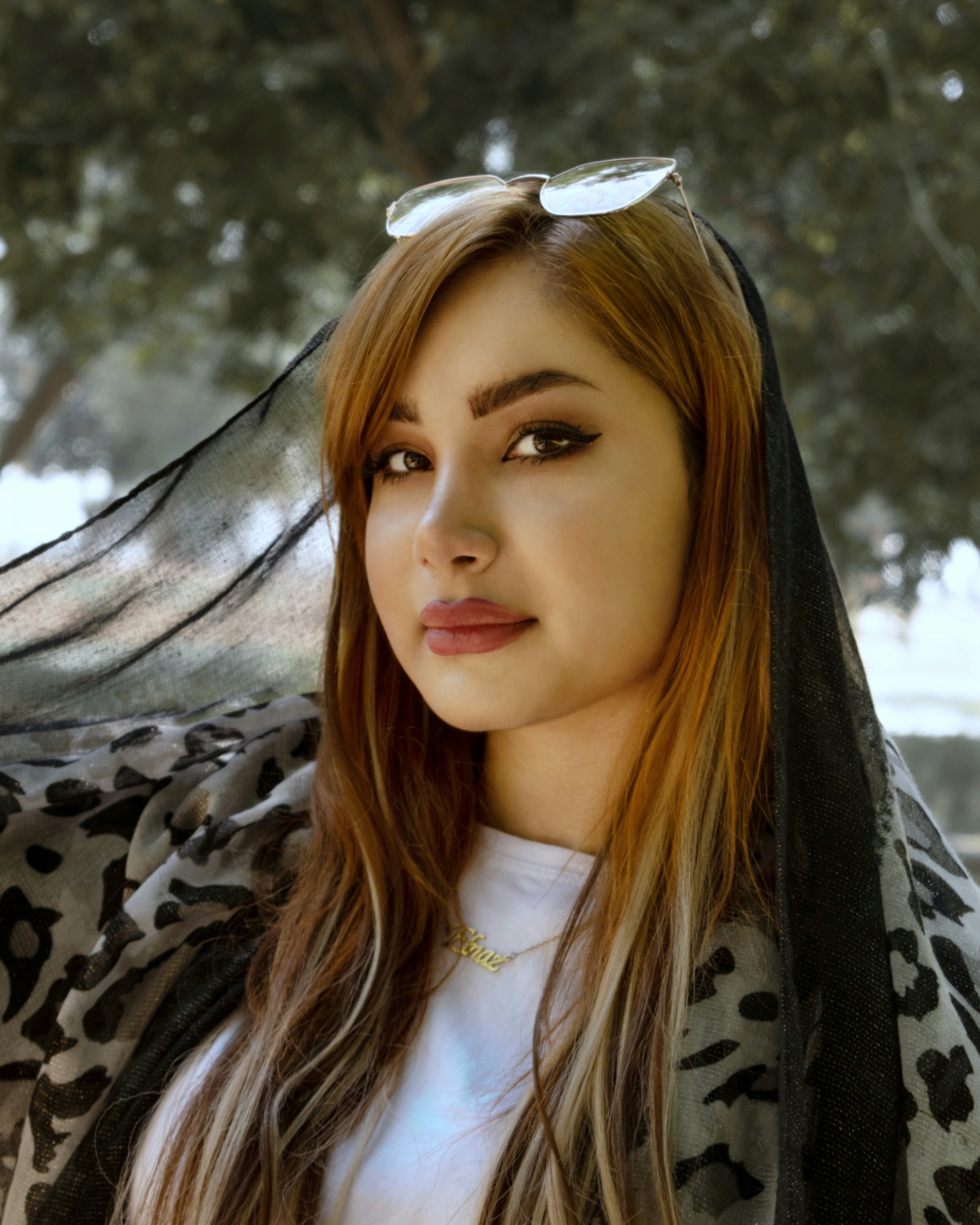 woman in white shirt and black and gray scarf