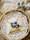 A woven basket holds an elegantly folded crepe dusted with powdered sugar and garnished with fresh blueberries. The crepe rests on a decorative white lace paper. In the background, ornate salt and pepper shakers are placed on a beige cloth napkin.