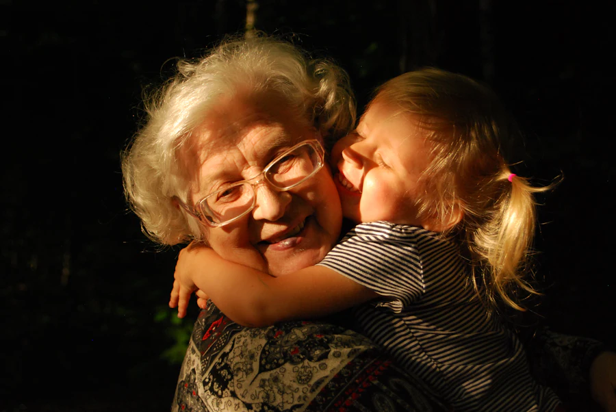An older woman with glasses embracing a young child.