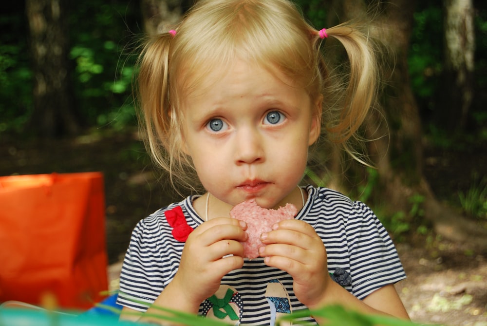 menina na camisa de manga comprida da listra azul e branca segurando o sorvete
