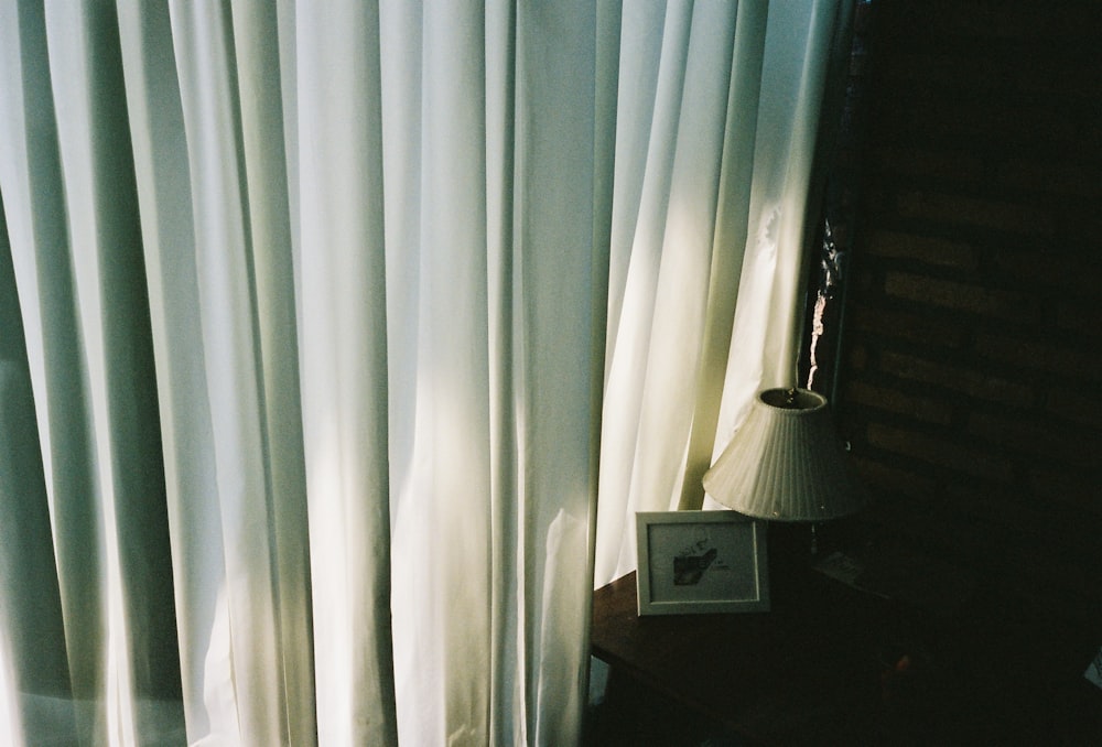 Weißer Fenstervorhang in der Nähe von weißer Tischlampe