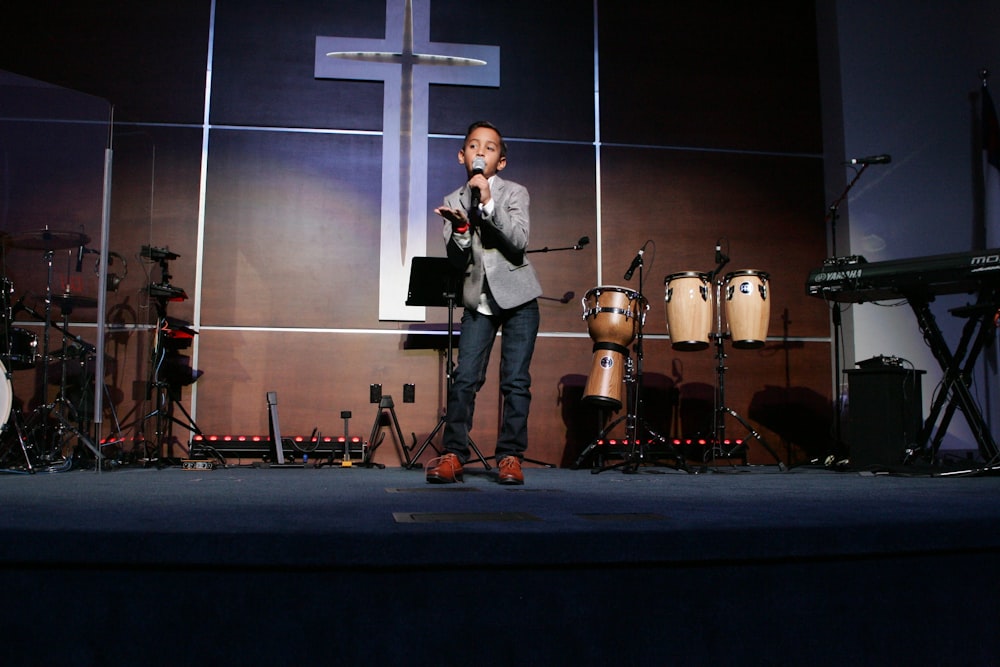 man in black suit standing on stage