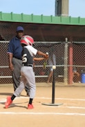 man in black and white jersey shirt and white pants holding baseball bat