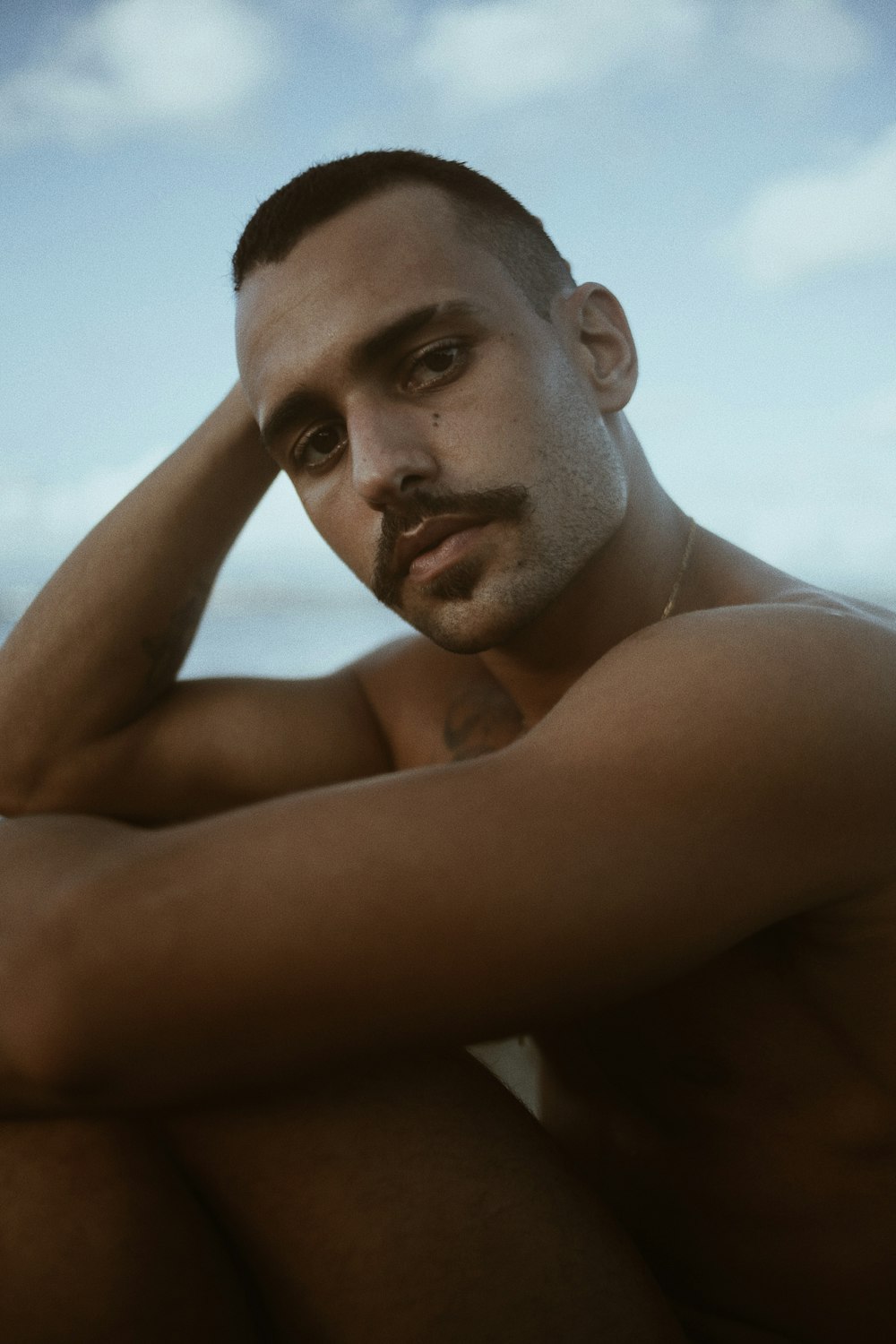 topless man sitting on white chair during daytime