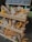 A display of various artisanal breads arranged on a wooden stand, accented with vibrant yellow sunflowers. The assortment includes different types of loaves and rolls, showcasing a rustic and inviting atmosphere. A chalkboard with writing is positioned above the breads.