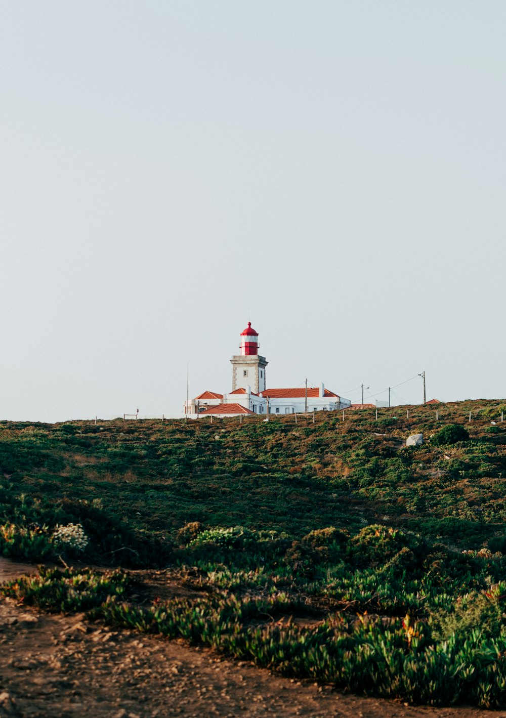 white and red lighthouse on green grass field under white sky during daytime