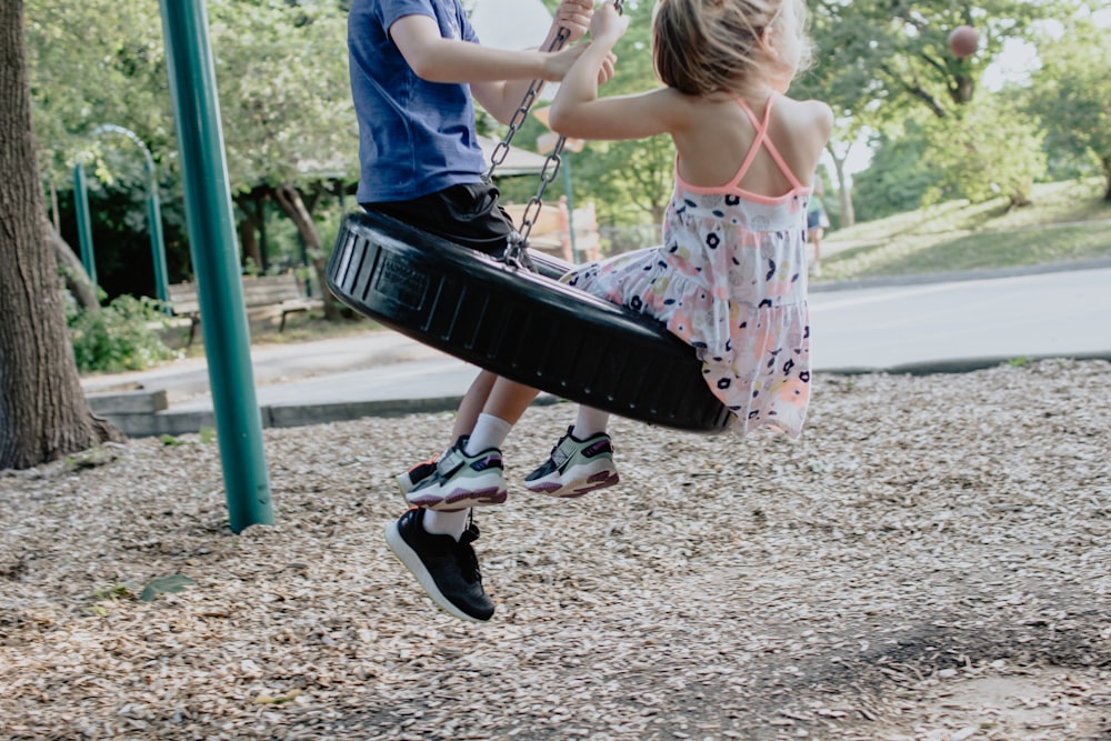 girl in pink and white floral dress riding on swing during daytime