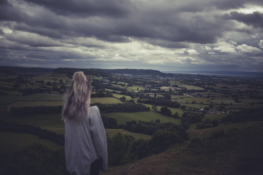 woman in gray hoodie standing on green grass field during daytime