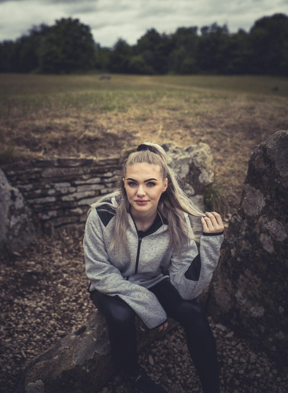 girl in gray jacket sitting on rock during daytime