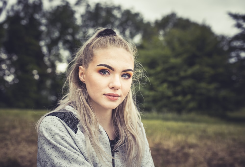 a woman with long hair sitting in a field