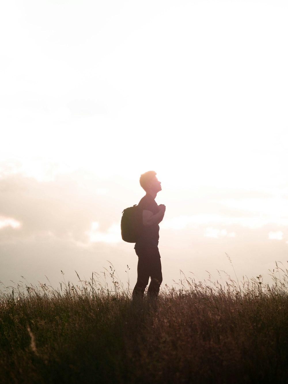 silhouette of man standing on grass field during sunset