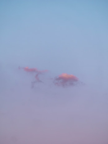 A soft pastel blue sky at dawn with gentle clouds drifting.