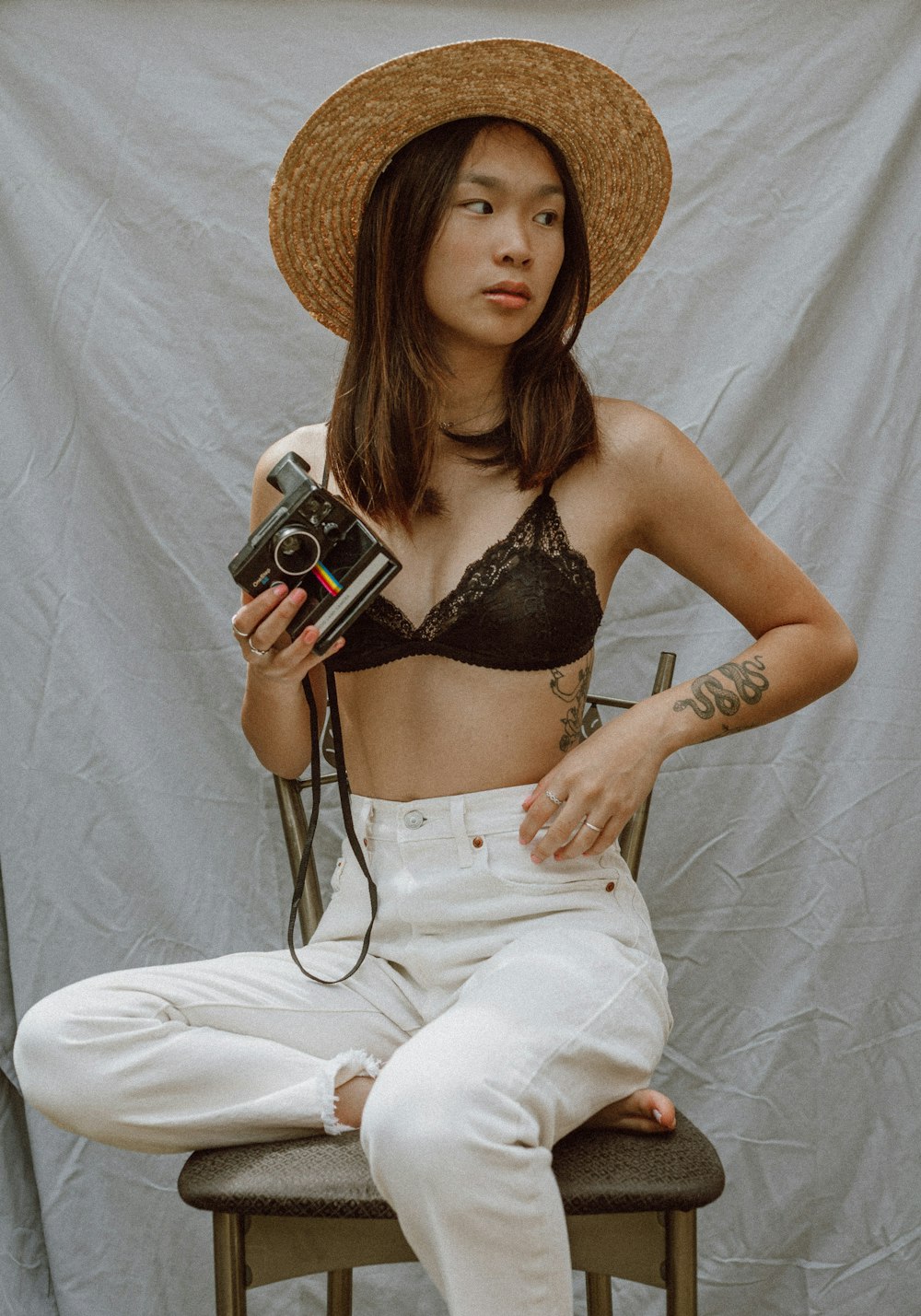 woman in black brassiere and white pants holding black and silver camera